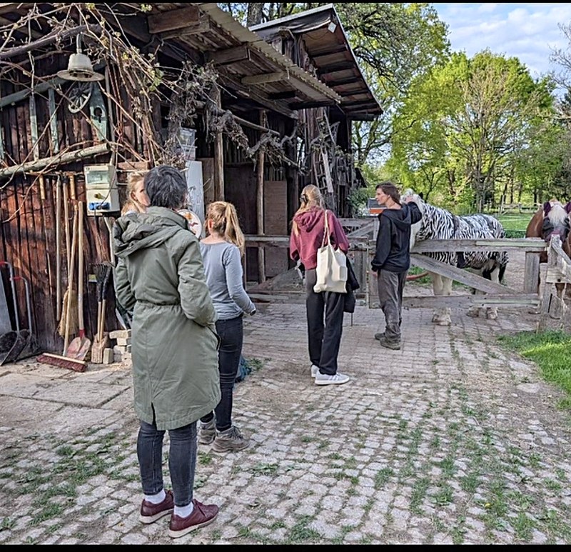 Eine Gruppe steht vor dem alten Stall im Hof